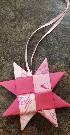 a pink and white origami star with the word help on it's side