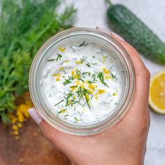 a person holding a small glass bowl filled with yogurt and garnish