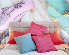 a bed topped with pillows next to a wall covered in colorful marbled walls and flooring