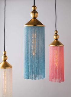 three different colored lights hanging from black cords and gold fixtures with fringes on them