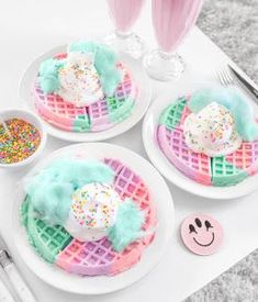 three white plates topped with waffles covered in frosting and sprinkles