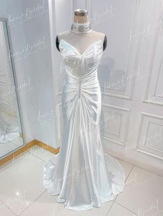 a white wedding dress on display in front of a mirror