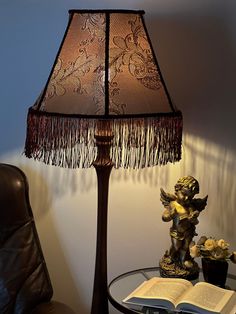 a lamp that is on top of a table next to a book and flower vase