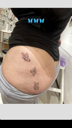 a woman's stomach with three small butterflies on the lower part of her belly