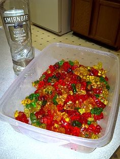 a plastic container filled with gummy bears next to a bottle of water on a counter