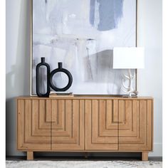 an abstract painting hangs on the wall behind a wooden cabinet