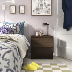 a bed room with a neatly made bed next to a night stand and pictures on the wall