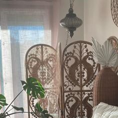 a bed with white sheets and pillows next to a window in a room filled with plants