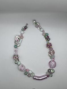 Pulling from the delicate and sweet color pallet of a petit four, this necklace features light green, baby pink, and white beads. The beads are of various shades, transparencies, shapes, and sizes. There are glass beads, freshwater water pearls, jade beads. They are beautifully suspended on three strands of silver-toned wire. The necklace is 14 inches long with a toggle clasp. Cute Pink Necklaces With Tiny Beads, Handmade Sweet Pink Necklace, Handmade Pink Sweet Necklace, Pink Handmade Sweet Necklace, Pink Glass Beaded Necklaces For Gift, Pink Glass Beaded Necklace For Gift, Whimsical Pink Beaded Necklaces With Round Beads, Pink Glass Necklace With Round Beads, Pink Single Strand Glass Necklace