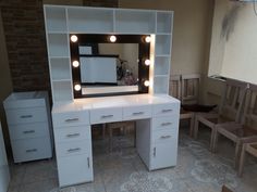 a white vanity with lights on it in front of a mirror and bench next to a brick wall