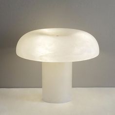 a mushroom shaped table lamp sitting on top of a white counter next to a gray wall