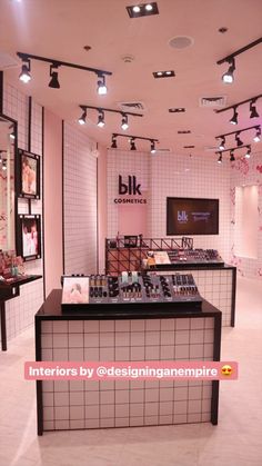 the interior of a cosmetics store with pink walls and black counter tops, white tile flooring and chandeliers hanging from the ceiling