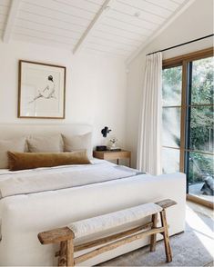 a bedroom with white walls and wooden furniture in front of a sliding glass door that leads to an outside deck