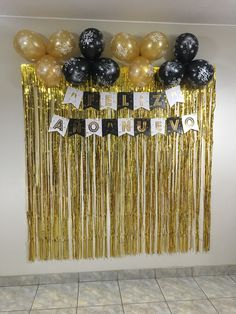 some black and gold balloons are hanging on the wall