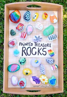 a wooden tray with painted rocks on it and the words painted treasure rocks written in black