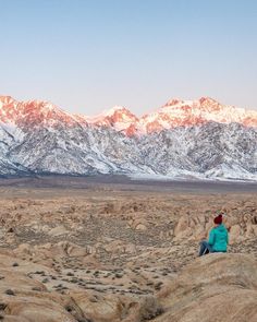 a person sitting on top of a rock in the desert