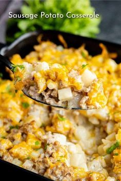 sausage potato casserole in a black baking dish with a spoon full of the casserole