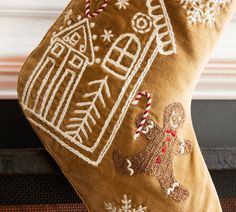 an embroidered christmas stocking with gingerbreads and a ginger house on it's side