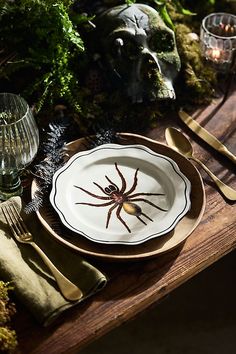 there is a plate with a spider on it next to some silverware and candles