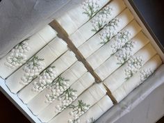 several napkins with white flowers and green stems on them are arranged in a box