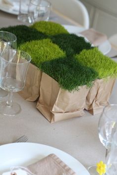 the table is set with napkins, glasses and paper bags that look like grass