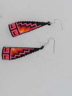 New Native American handmade beaded dangle earrings with vibrant pink, black, and red beads. Hang approximately 2" long. By Navajo artist Denise Goldtooth. These earrings are a celebration of vibrant color and traditional craftsmanship, featuring a harmonious blend of pink, black, and red beads that come together to form a captivating design. Each bead is meticulously handwoven, showcasing Denise’s dedication to her craft and her deep-rooted connection to her Navajo heritage. Measuring approximately 2 inches in length, these earrings offer a perfect balance of elegance and statement-making style. Their lightweight design ensures comfortable wear, while the vivid colors add a striking accent to any outfit, making them ideal for both everyday wear and special occasions. Whether you're lookin Pink Large Beads Dangle Earrings, Pink Large Beaded Dangle Earrings, Pink Dangle Beaded Earrings With Large Beads, Pink Dangle Beaded Earrings With Black Beads, Pink Beaded Earrings With Black Beads For Gift, Artisan Black Beaded Drop Earrings, Adjustable Pink Earrings With Large Beads, Pink Large Bead Dangle Earrings, Red And Black Beaded Festival Earrings