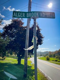 the street sign for alger brook road is posted on an old telephone pole in front of some trees