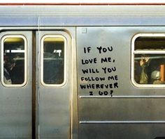 a subway car with graffiti written on the side and people sitting in the window looking out