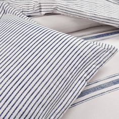 blue and white striped bedding with two pillow cases next to each other on a bed