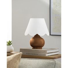 a lamp that is on top of some books in front of a couch and table