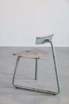 a metal chair sitting on top of a cement floor next to a white wall in an empty room