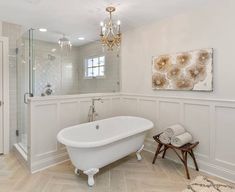 a white bath tub sitting under a chandelier next to a walk in shower