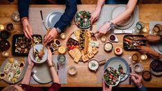 people sitting at a table with plates and bowls of food in front of their hands