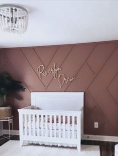 a baby's room with pink walls and white crib in the corner, along with a chandelier