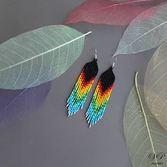 a pair of colorful beaded earrings sitting on top of a table next to leaves