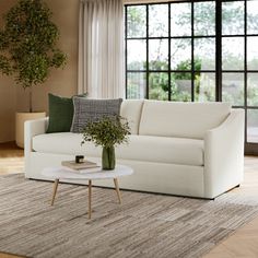 a living room scene with focus on the couch and coffee table in front of the window