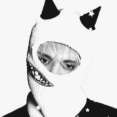 a man wearing a white mask with black stars on his face and nose, in front of a white background