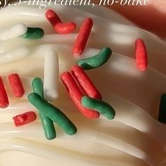 a close up of a cupcake with white frosting and red and green sprinkles