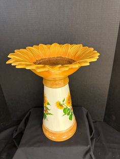 a yellow and white vase with flowers painted on it