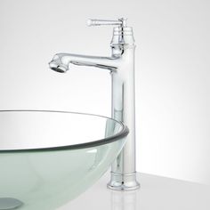 a clear glass bowl sink with chrome faucet and matching faucet handles