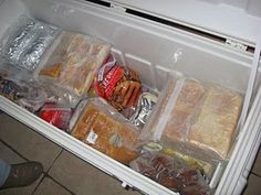 an open refrigerator filled with food and plastic wrappers on the door, next to someone's feet