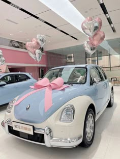 a car is decorated with pink and silver heart balloons for valentine's day in a showroom