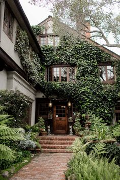 a house covered in vines and greenery with stairs leading to the front door