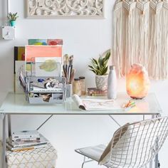 a white desk topped with lots of clutter next to a wall mounted art piece