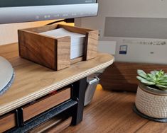 a wooden box sitting on top of a table next to a plant