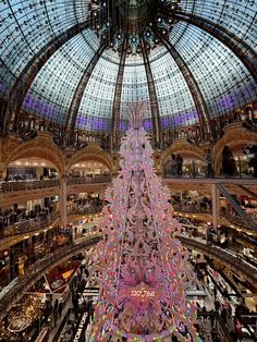 a large christmas tree in the middle of a shopping mall with lots of lights on it