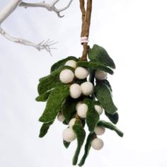 an ornament hanging from a tree branch with white balls and leaves