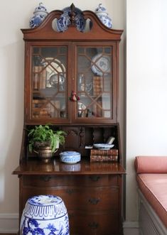 an old china cabinet with blue and white vases on it's top shelf