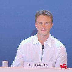 a man sitting at a table with a microphone in front of him and the words d starkey on it