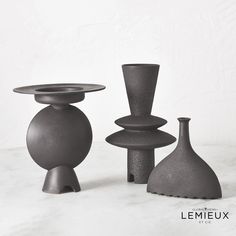 three black vases sitting next to each other on a table